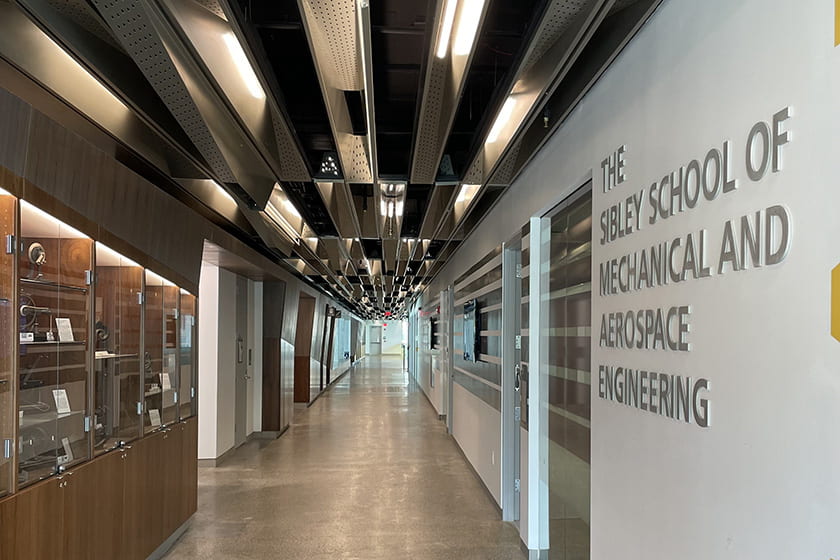 A photograph of a hallway inside Upson Hall with a sign on the wall that reads The Sibley School of Mechanical and Aerospace Engineering
