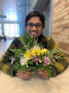 A photo of a Cornell Engineering student, holding a flower arrangement