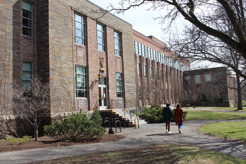 A photograph of two students walking in front of Olin Hall