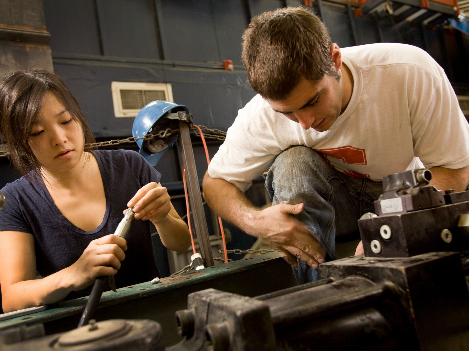A photograph of two students working on a car engine