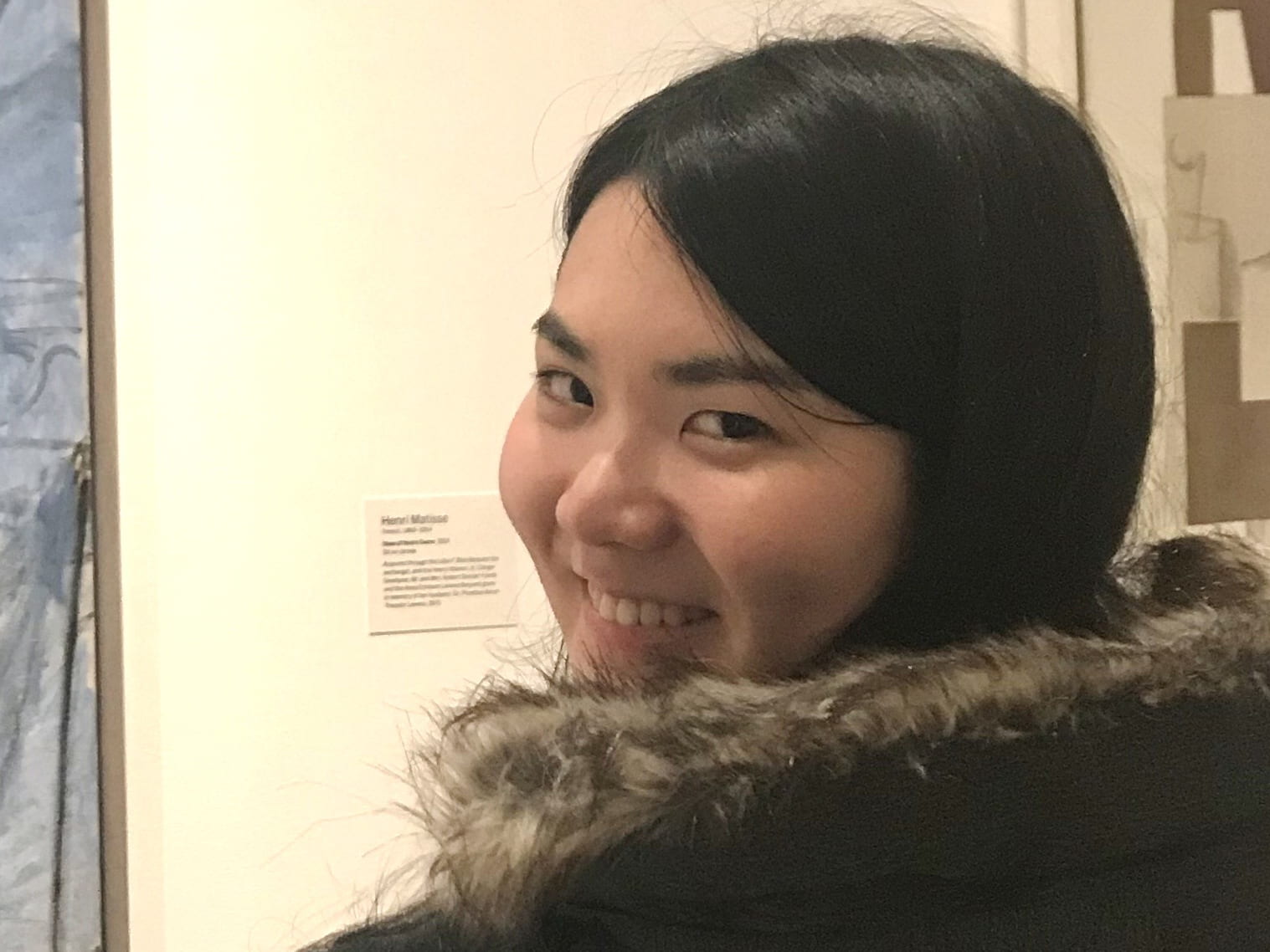 A photograph of Cornell ENgineering student Reina in front of a painting